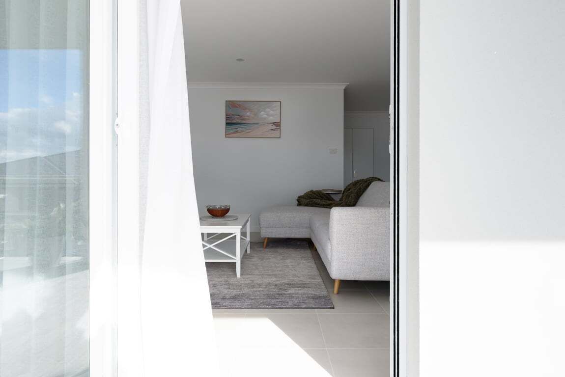 Ein modernes Wohnzimmer mit einem grauen Sofa, einem kleinen weißen Tisch mit einer Schale und einem Bild an der Wand.