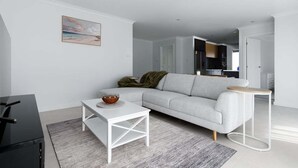 A modern living room with a grey sofa, white coffee table, and a small side table. - Wake Up to Stunning Tamar Valley Views (Riverside)