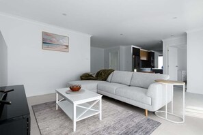 Ein stilvolles Wohnzimmer mit grauem Sofa, weißem Couchtisch und einem kleinen Beistelltisch.