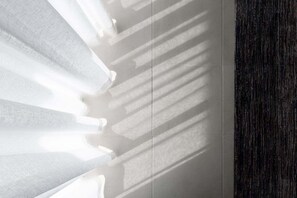 Ein Zimmer mit einem großen Fenster, das Schatten an die Wand wirft.