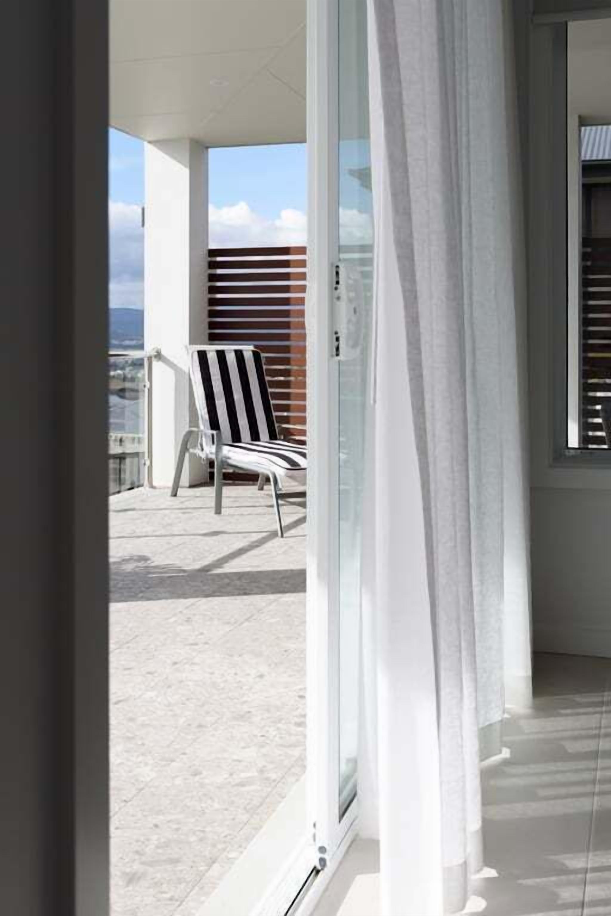 Een balkon met een witte stoel en uitzicht op de stad.