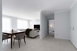 A modern living space with a dining area, a sofa, and a television. - Wake Up to Stunning Tamar Valley Views (Riverside)