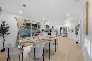 A modern kitchen with white cabinets, stainless steel appliances, and a dining area with a wooden table and chairs. - Pool, Big Yard, View, King Bed, Parking, 4BR - 2.5Bth (El Cajon)