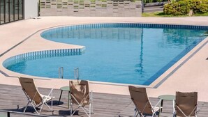 A swimming pool with a curved edge, surrounded by lounge chairs and a deck. - Yunseulga Bada (Seoul)