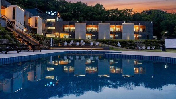 A modern hotel with a swimming pool, outdoor seating, and a view of the surrounding landscape. - Yunseulga Bada (Seoul)
