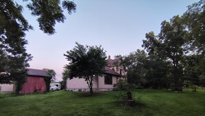 A residential property with a red barn, a pink house, and a grassy yard.