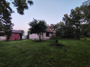 A residential property with a red barn, a pink house, and a grassy yard.