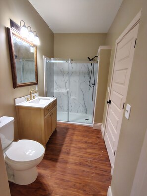 A bathroom with a toilet, sink, vanity, and a glass-enclosed shower.