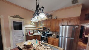 A kitchen with wooden cabinets, a stainless steel refrigerator, a sink, and a wooden drying rack.