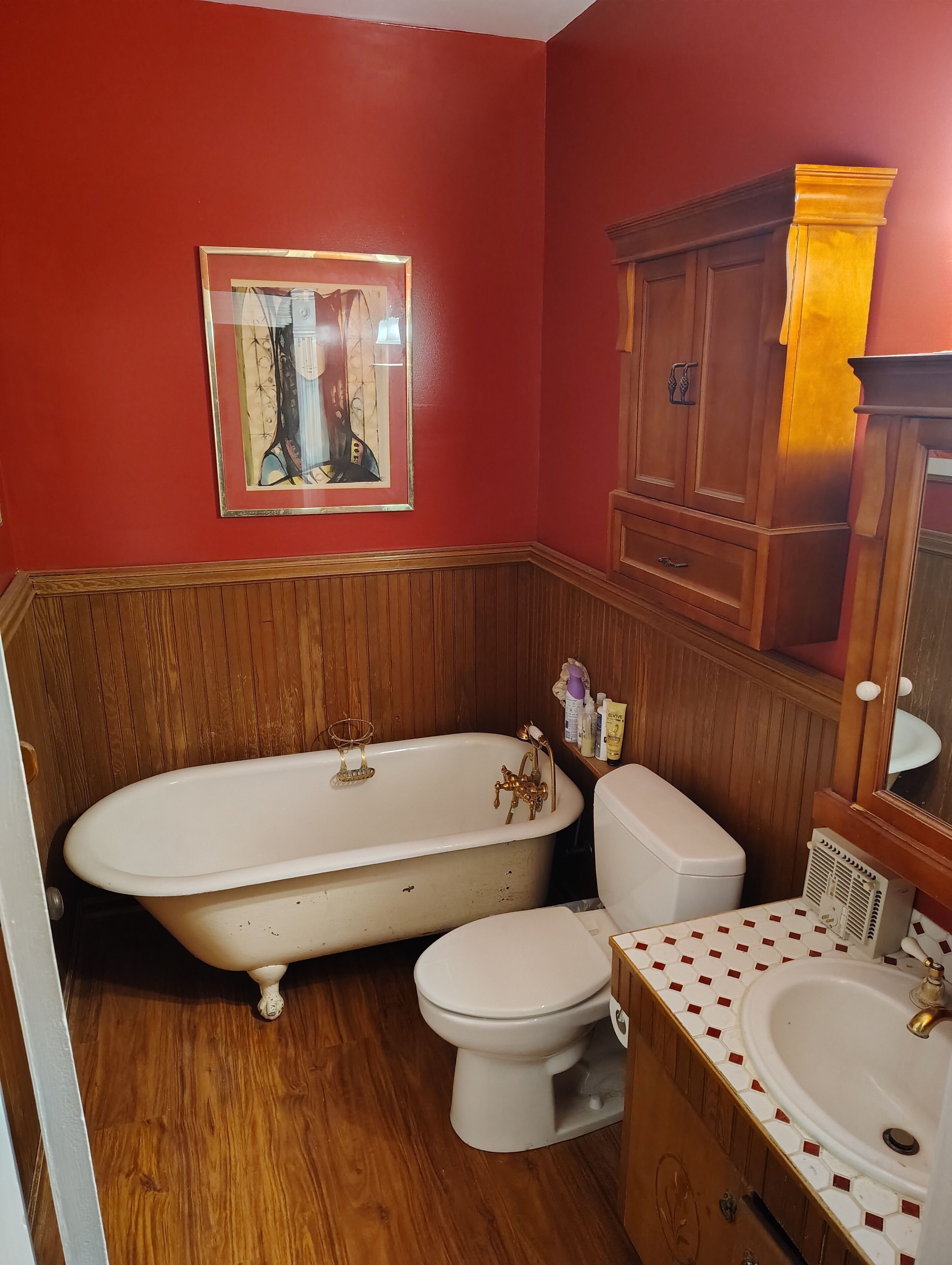 Um banheiro com banheira de madeira, vaso sanitário e pia com bancada revestida em azulejo.