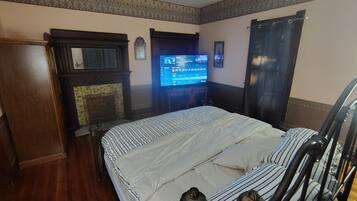 Quarto de hotel com cama, televisão, lareira e cortina.