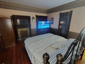 Una habitación de hotel con una cama, televisión, chimenea y cortina.