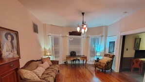 A living room with a wooden floor, a sofa, a chair, a table, and a chandelier.