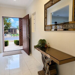 A modern entryway with a glass door, a bench, and a decorative mirror.