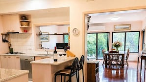 Una cucina moderna con isola centrale, zona pranzo con sedie in legno e ampie finestre che offrono vista sul verde.