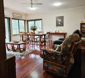Ein Wohnzimmer mit Essbereich, Holzmöbeln und großen Fenstern.