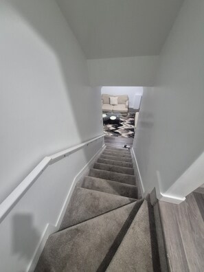 A carpeted staircase with a handrail, leading to a room with a sofa and a rug. - Elegant West Edmonton Escape (Edmonton)