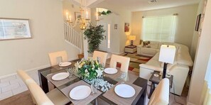 Comedor con mesa de vidrio dispuesta para cuatro personas, rodeado de sillas.