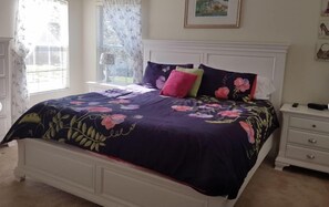 A bedroom with a bed, a nightstand, a dresser, and a window with curtains. - 648 - Spacious 6-Bedroom Emerald Island Retreat with Pool, Spa & Games Room Near Disney (Kissimmee)