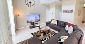 Een woonkamer met een bank, televisie en een decoratieve klok aan de muur.