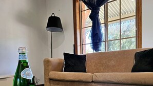 A living room with a sofa, a table with a magazine, a bottle of S. Pellegrino sparkling water, and a glass.
