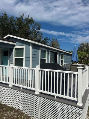 A single-story house with a porch, white picket railing, and a blue umbrella.