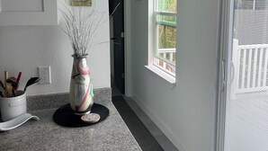 Eine Küche mit Granitarbeitsplatte, einer Dekovase und einer Tür zum Balkon.