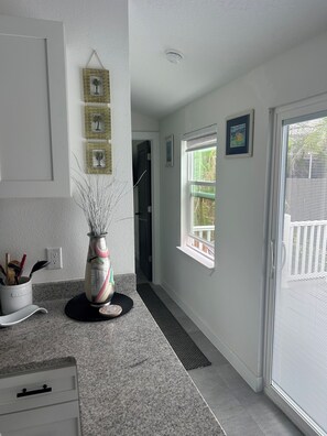 A kitchen with a granite countertop, a decorative vase, and a door leading to a balcony.