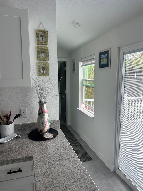 A kitchen with a granite countertop, a decorative vase, and a door leading to a balcony.