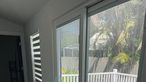 Ein Zimmer mit einer Schiebetür, die auf einen Balkon mit weißer Brüstung im Freien führt.