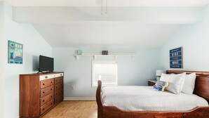 Ein Schlafzimmer mit einem hölzernen Bett, einem Schminktisch, einem Fernseher und einem Fenster mit Jalousien.