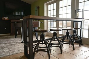 Un espace bar avec une table centrale et des tabourets.