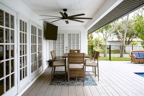 A covered patio with a dining table and chairs, a ceiling fan, and a view of the outdoors. - Heated Pool Home with Foosball/BBQ/Kids Playroom (Englewood)