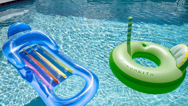 Ein Swimmingpool mit klarem Wasser und zwei aufblasbaren Schwimmreifen, ein blauer und ein grüner.
