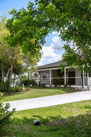 A residential house with a covered porch, a lawn, and a tree in the foreground. - Heated Pool Home with Foosball/BBQ/Kids Playroom (Englewood)