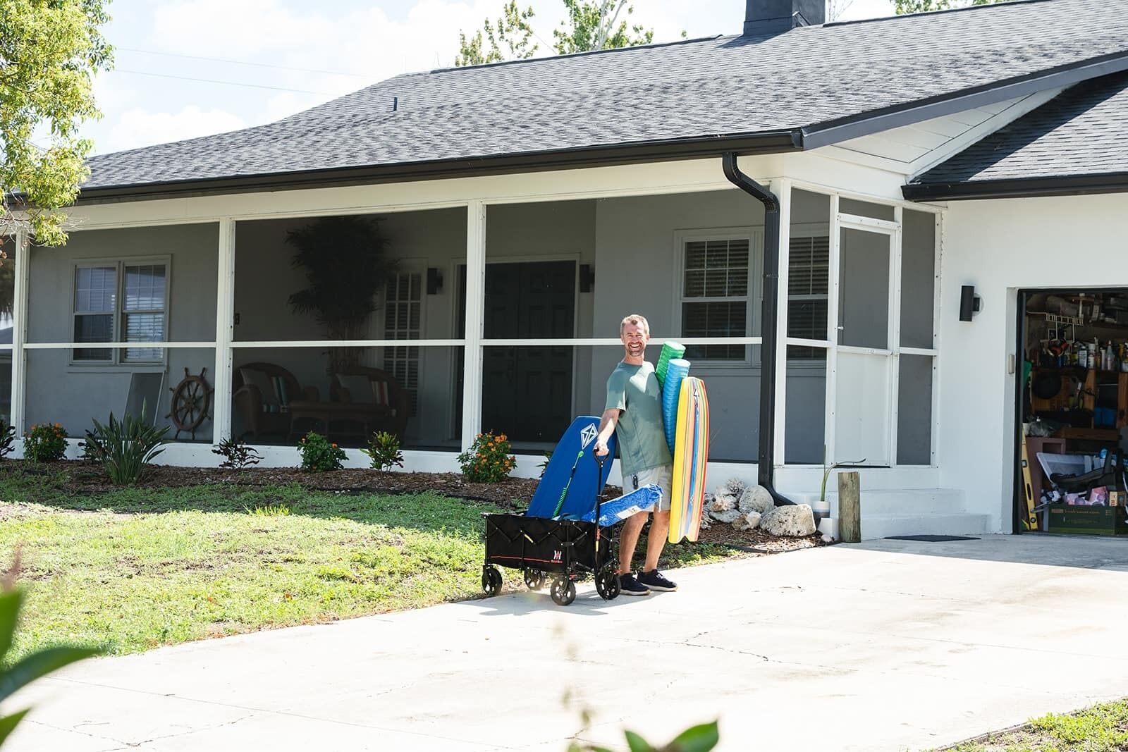 A house with a covered porch, a wheelchair, and a person holding surfboards.