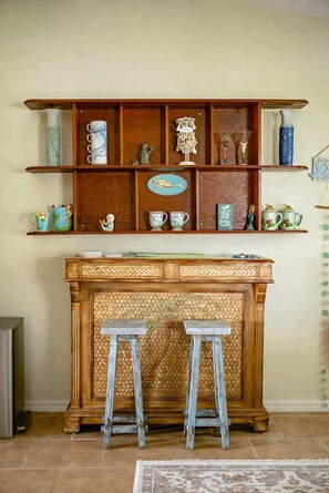 Un tavolo consolle in legno con due sgabelli di fronte, affiancato da mensole con oggetti decorativi.