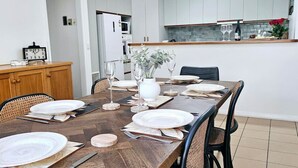 A dining area with a wooden table set for four, surrounded by chairs. - Garden Retreat on Orr – Your Peaceful Hideaway (Shepparton)