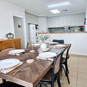 A dining area with a wooden table set for four, surrounded by chairs. - Garden Retreat on Orr – Your Peaceful Hideaway (Shepparton)