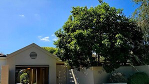 A building with a garage entrance, a tree in front, and a clear sky. - Garden Retreat on Orr – Your Peaceful Hideaway (Shepparton)