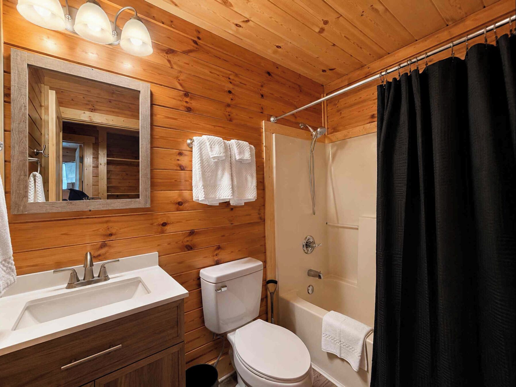 Baño con detalles de madera que incluye un lavamanos, inodoro y ducha.