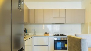 A compact kitchen with a refrigerator, stove, oven, and white cabinets.