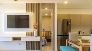 Eine moderne Küche mit Einbaukühlschrank, ein Essbereich mit einer Bank und ein Wohnbereich mit Flachbildfernseher.