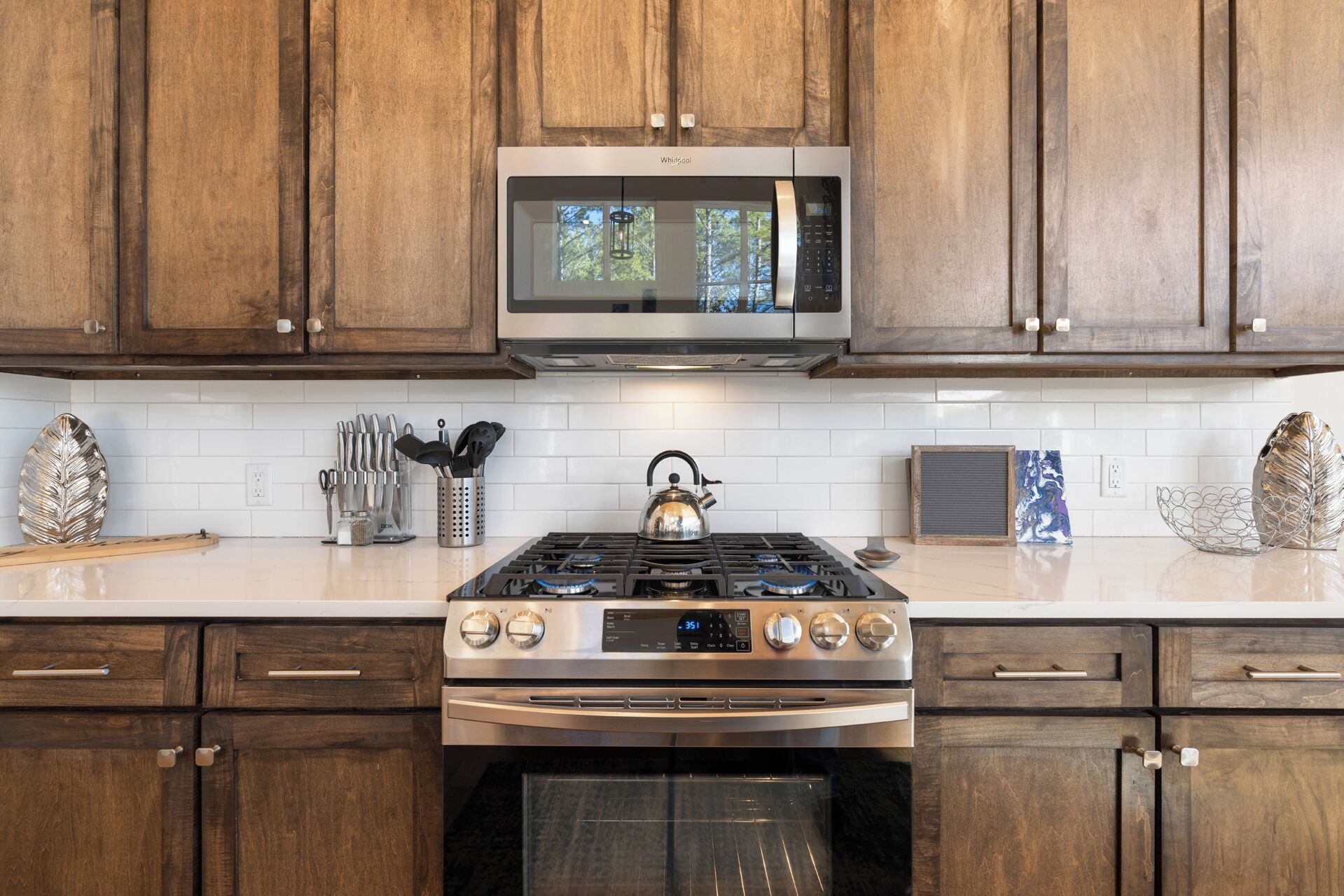 A kitchen with wooden cabinets, a stainless steel microwave, a gas stove, and an oven.