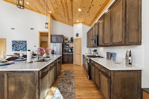A spacious kitchen with wooden cabinets, a large island, and a wooden ceiling. - Fall Promo! Modern • Mini Golf • Hot Tub • Hot Tub (Broken Bow)