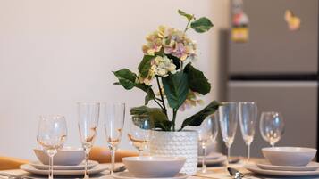 A dining table set with multiple plates, bowls, and wine glasses, with a potted plant in the center.