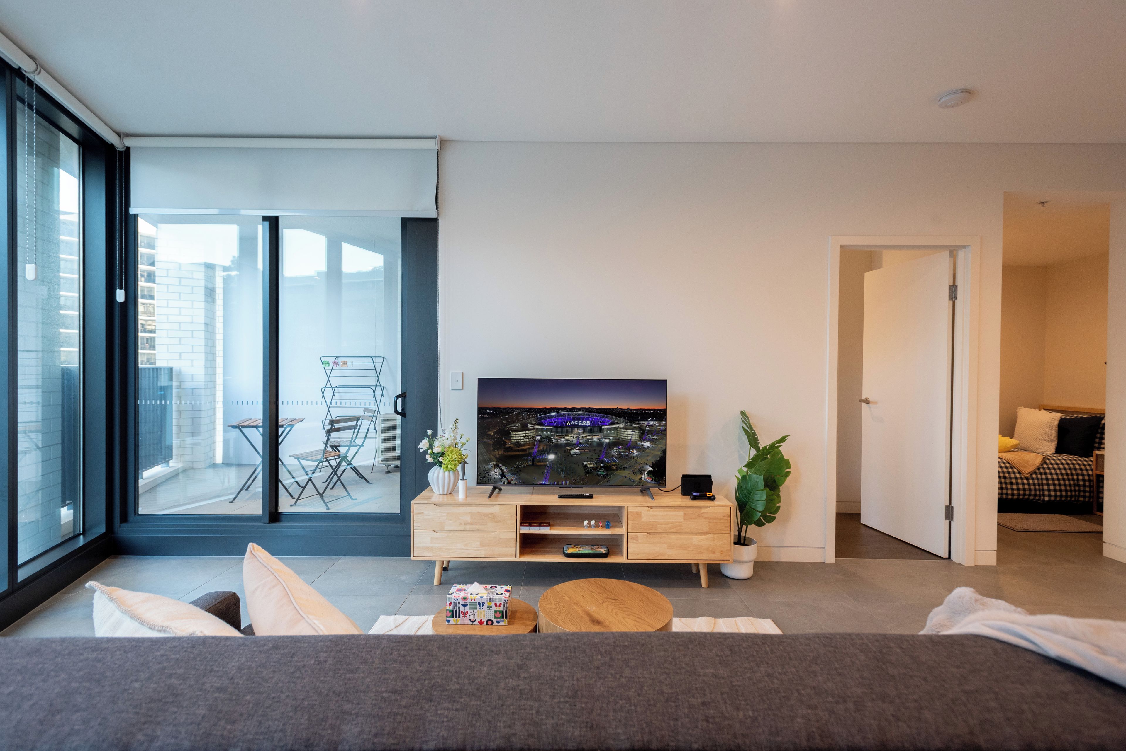 A modern living room with a flat-screen TV, a wooden coffee table, and a sofa.