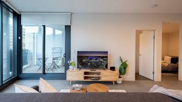 A modern living room with a flat-screen TV, a wooden coffee table, and a sofa.