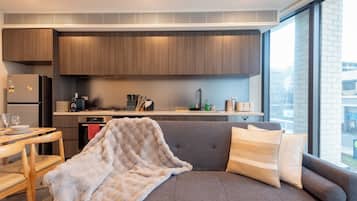A modern kitchen with wooden cabinets, a dining area with a table and chairs, and a large window providing a view of the outside.
