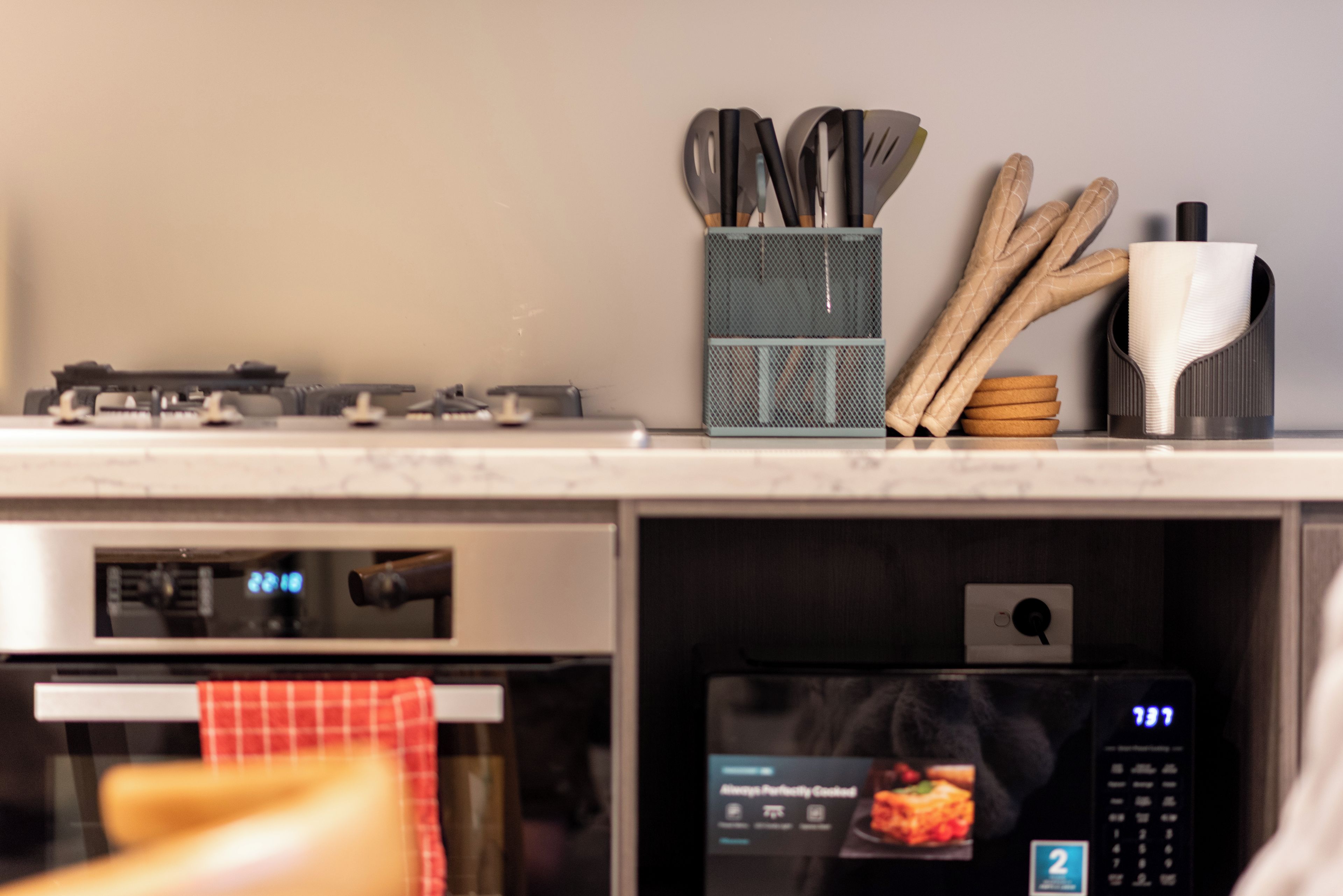 A kitchen with a stove, oven, and microwave. There are utensils and a spatula holder on the counter.